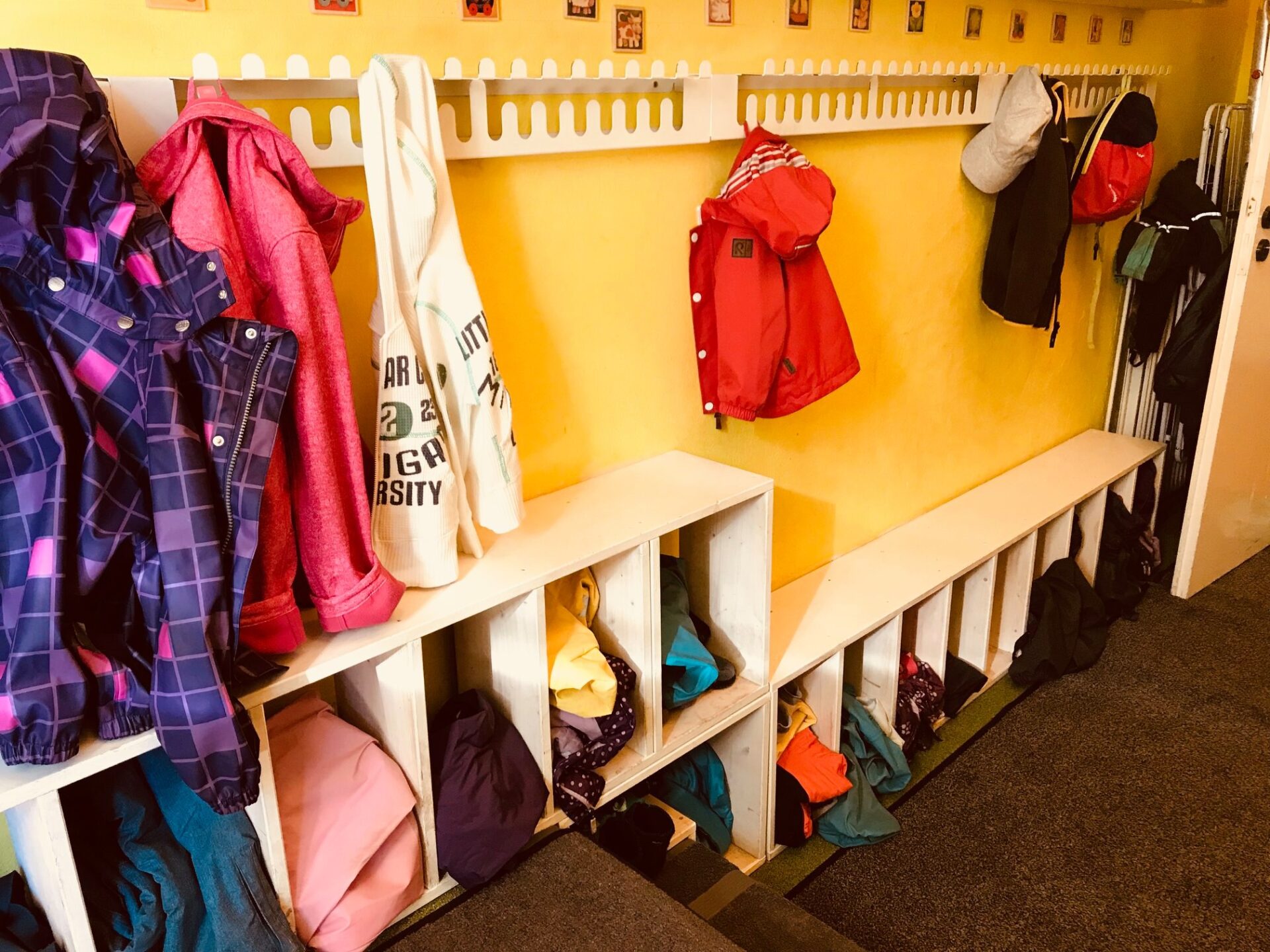 Entrance area of the daycare center with a wardrobe where children's clothes are hanging.