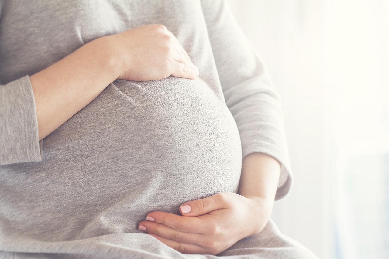 Eine Frau hat ihre Hände auf ihrem schwangeren Bauch.